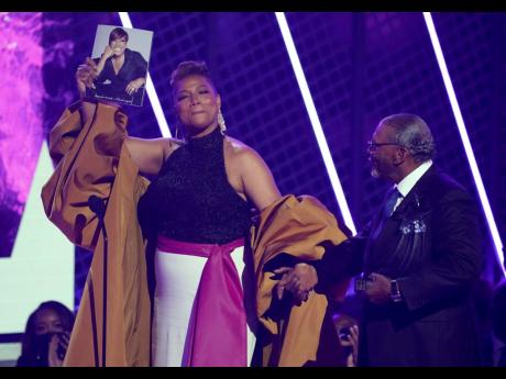 Queen Latifah, winner of the Lifetime Achievement Award, holds a photo of her late mother, Rita Owens, as she walks with her father, Lancelot Owens Sr, at the BET Awards on Sunday. 