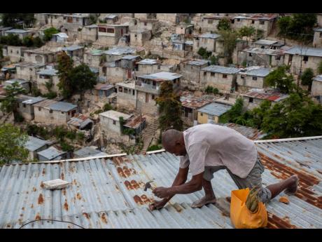 Antony Exilien secures the roof of his house in response to Tropical Storm Elsa, in Port-au-Prince, Haiti, yesterday, which brushed past Haiti and the Dominican Republic.