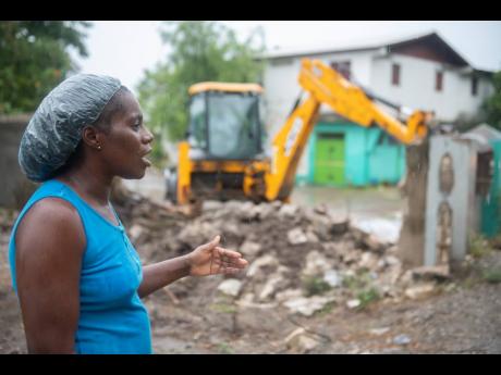 Hartence Sharpe talks about Sunday’s flooding as a tractor creates a barrier to divert the flow of water away from her home. Tropical Storm Elsa caused waist-high flooding at her home. 