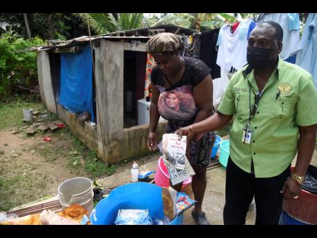 Latoya Hedge, a resident of Church Road, Bog Walk, and JLP Councillor Peter Abraham, Bog Walk division go through school books belonging to Hedge’s children which were damaged by flood rains associated with Tropical Storm Elsa on Sunday.