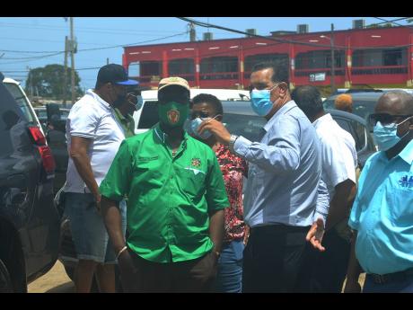 Credit: Contributed Desmond McKenzie (left foreground) minister of local government converses with Homer Davis, state minister for local government, during a tour of the Charles Gordon Market in Montego Bay on Friday.