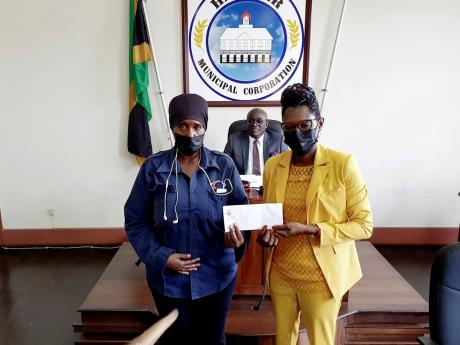 Hanover municipal police officer, Nicole Bookal (left), accepts a cash award for her professional services from Deputy Mayor of Lucea Councillor Andria Dehaney-Grant, while Lucea Mayor Sheridan Samuels (centre) looks on.