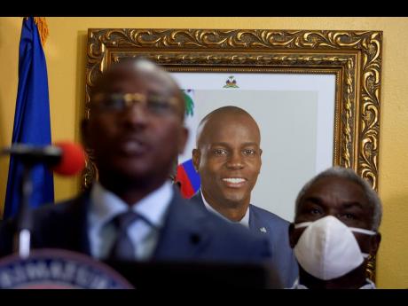 A picture of late Haitian President Jovenel Moïse hangs on the wall of his former residence, behind interim Prime Minister Claude Joseph during a press conference in Port-au-Prince on Tuesday, July 13. Moïse was assassinated in his home on July 7.
