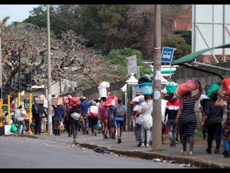 People make their way from a shopping mall carrying goods looted in Durban, South Africa, yesterday.