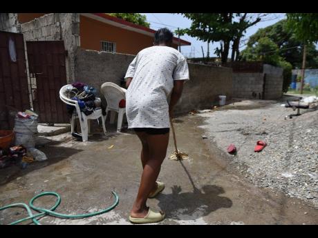 Credit: Kenyon Hemans/Photographer A resident from Torrington Park in Kingston was seen cleaning blood from a hairdressing salon on Tuesday after a gunman shot and injured two women the night before.
