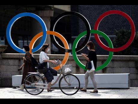 People walk by the Olympic rings installed by the Nippon Bashi bridge in Tokyo yesterday.