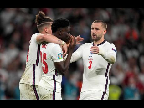 
England’s Bukayo Saka (centre) is comforted after he missed to score the last penalty during the penalty shootout of the Euro 2020 soccer championship final between England and Italy at Wembley stadium in London, Sunday, July 11.