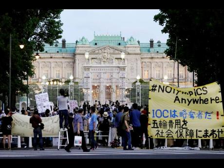 Credit: AP Protesters against the Tokyo Olympics gather outside Akasaka Palace, a Japanese state guest house, where the welcome party for IOC President Thomas Bach and its officials were held in Tokyo yesterday. The banner at right reads 'IOC is a looter! Use Olymp