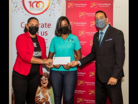 Charlene Reid (left), senior associate pastor, Go For God Family Church, and Ella Gartley, leader, Outreach Ministry, receive a cheque from Nigel Holness, managing director, CIBC FirstCaribbean, in support of their Food Drive Outreach Programme.  The initi