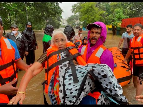 Credit: AP A National Disaster Response Force personnel rescues an elderly woman stranded in floodwaters in Kolhapur, in the western Indian state of Maharashtra yesterday.