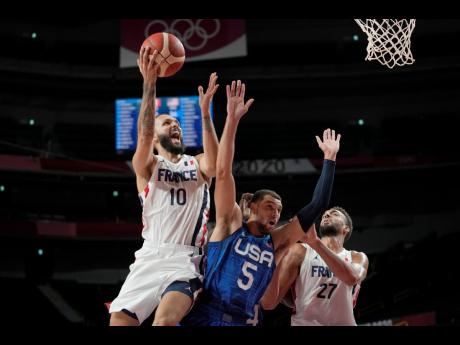 France’s Evan Fournier (left) shoots over United States of America guard Zachary Lavine (centre) during a men’s basketball preliminary-round game at the Tokyo Olympic Games in Saitama, Japan, yesterday.