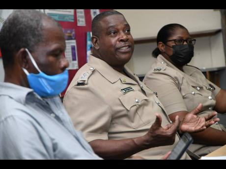 Senior Superintendent of Police Gary McKenzie (centre), head of the Police Safety and Traffic Enforcement Branch, addresses a meeting of the Transport Operators Development Sustainable Services (TODSS) at Half-Way Tree Primary School on Sunday. He is flank