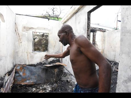 Credit: Kenyon Hemans/Photographer Oscar Palmer walks through one of the scorched rooms in his Kingston Gardens home on Tuesday. Arsonists attacked the family before dawn.