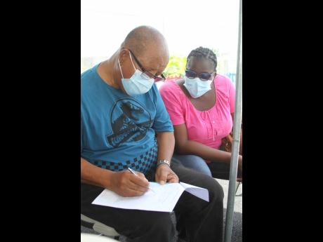 Thaddeus Blight filling out a form for his first dose of the AstraZeneca vaccine at Denbigh Primary School during the vaccination blitz. Beside him is his wife Veronica, who is fully vaccinated. 