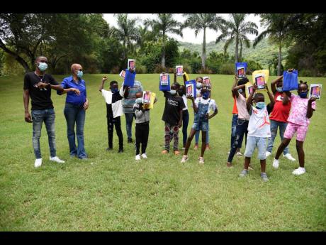 left: Founder of a community summer school programme, Jaheim Brown (left), poses with Education Minister Fayval Williams and students of his who received 15 tablets, Hope Zoo passes, and KFC lunches on Saturday.