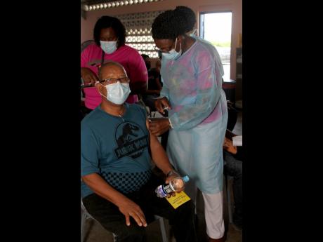 Nurse Nadine Rowe administers the first dose of the AstraZeneca vaccine to Thaddeus Blight, who was encouraged by his wife, Veronica, to get vaccinated. Scores of persons turned out on Saturday at Denbigh Primary School to receive their first or second dos