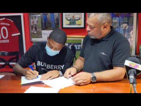 Credit: Contributed Reggae Boy Leon Bailey (left) made his move to the English Premier League official when he signed a contract with Aston Villa Football Club yesterday. The signing took place at the Phoenix All Stars Academy headquarters in Kingston. Looking on is his adopt