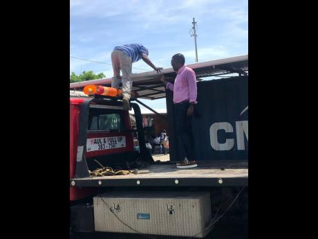 Craig Oates (right), enforcement and compliance officer at the Hanover Municipal Corporation, and a flatbed truck operator loading the seized items belonging to illegal vendors onto the truck.
