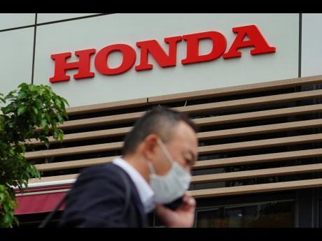 AP 
A man wearing a protective mask to help curb the spread of the coronavirus walks past the logo of Honda Motor Company in Tokyo on May 13. Honda returned to profitability in April-June, recording a 222.5-billion yen ($2-billion) profit, as better sales 