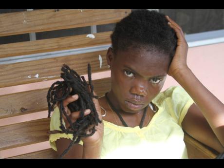 Credit: Nathaniel Stewart Nzinga King, 19, with a handful of dreadlocks she saved, which were allegedly trimmed by a cop.