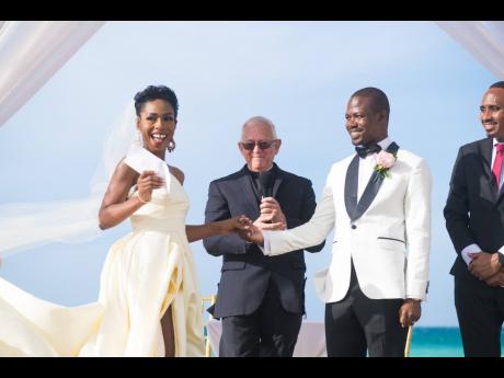Credit: Ramesh Newell Officiating Minister, Reverend Ronnie Thwaites (centre), appears pleased as Dr Nordia Thompson-Newell (left), proudly displays the official document in one hand, while husband, Omar Newell, holds the other. Looking on is best man, Lenroy James.