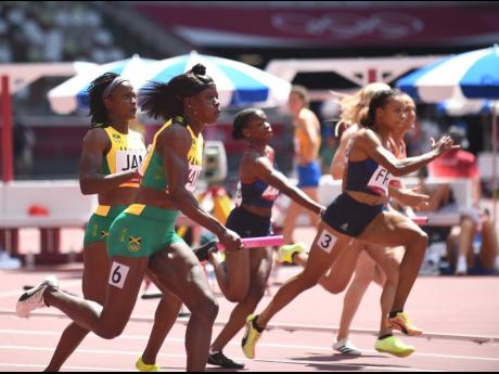 Shericka Jackson (foreground) collects the baton from Remona Burchell to snatch third place and a spot in the final of the 4x100m at the Tokyo Olympic Stadium in Tokyo, Japan during the Olympic Games, on Thursday.