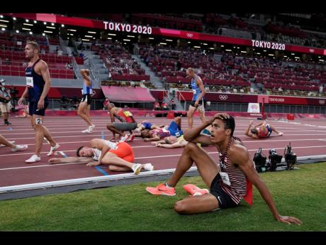 Competitors rest on the track after the Decathlon 1500m event at the 2020 Summer Olympics, in Tokyo, Japan, yesterday.