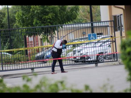 A policeman processes the scene where Granville gangster Oryon ‘Chef’ Williams was shot dead in the visitors’ parking lot of Vista Print in Montego Bay, St James, yesterday.