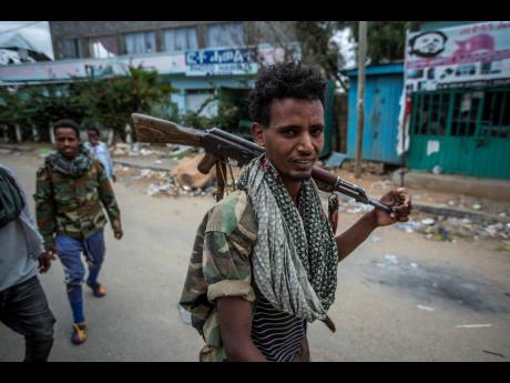FILE - In this Friday, May 7, 2021 file photo, fighters loyal to the Tigray People’s Liberation Front (TPLF) walk along a street in the town of Hawzen, then-controlled by the group, in the Tigray region of northern Ethiopia. 