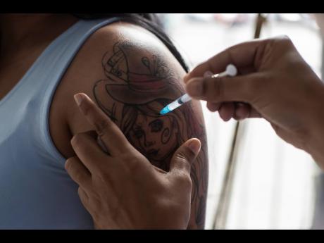 A woman gets a shot of the Pfizer vaccine for COVID-19 during a vaccination campaign for women over age 31 in Sao Joao de Meriti, Brazil, Wednesday, August 11, 2021. 