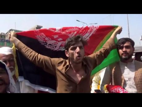 A man holds the flag of Afghanistan during a protest in Jalalabad on Wednesday, August 18. 