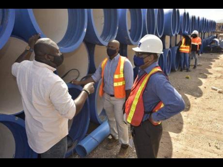 Credit: JIS Senior design engineer at the National Water Commission (NWC), Erron Reid (left), in discussion with Deputy Managing Director of M&M Jamaica Limited Richard Mullings (centre) and Vice-President of the National Water Commission Garth Jackson, while at the S