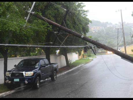 A motorist attempts to ‘squeeze’ pass a downed power line on Retreat Avenue, St Andrew, during the passage of Tropical Storm Grace.