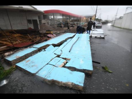Workmen attempt to secure this construction site on Beechwood Ave, Kingston, after heavy rainfall associated with Tropical Storm Grace flatten the wall.