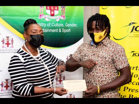
The Minister of Culture, Gender, Entertainment and Sport Olivia Grange, makes a presentation to the winner of the Jamaica 60 logo design competition, Bobby Smith.
