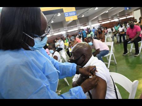 Rudolph Brown/Photographer 
Public health nurse Hopelyn Mullings administers a shot of the AstraZeneca COVID-19 vaccine to 68-year-old Trevor Bernard during a mass vaccination event at the National Arena on Tuesday, August 3, 2021.