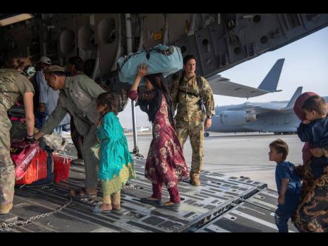 US Air Force loadmasters and pilots assigned to the 816th Expeditionary Airlift Squadron load people being evacuated from Afghanistan on to a US Air Force C-17 Globemaster III at Hamid Karzai International Airport in Kabul, Afghanistan, on Tuesday.