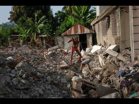 Michael Jules, an America des Cayes professional soccer player, searches for his passport among the remains of his grandmother’s collapsed house, in Maniche, Haiti onTuesday.
