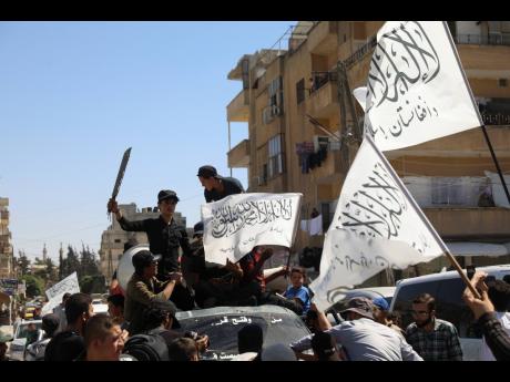
Members of the Hay’at Tahrir al-Sham, a Sunni Islamist militant group, wave the Taliban flags as they celebrate the Taliban takeover of Afghanistan, in the city of Idlib on Friday.