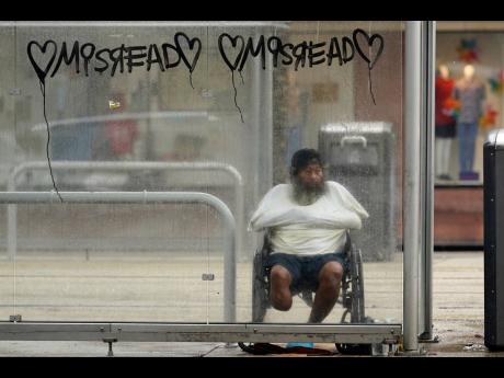 A man in a wheelchair takes cover in a bus stop shelter as Hurricane Ida makes landfall in New Orleans.