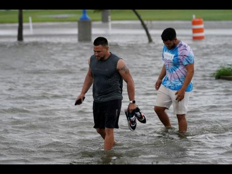 Jesse Perez (left) and Sergio Hijuelo walk through flooded streets near Lake Pontchartrain in New Orleans.