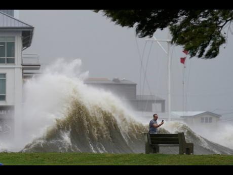 A man takes pictures of high waves along the shore of Lake Pontchartrain as Hurricane Ida nears on Sunday in New Orleans. 