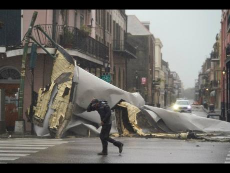 A man passes by a section of roof that was blown off a building in the French Quarter by Hurricane Ida winds on Sunday in New Orleans. 