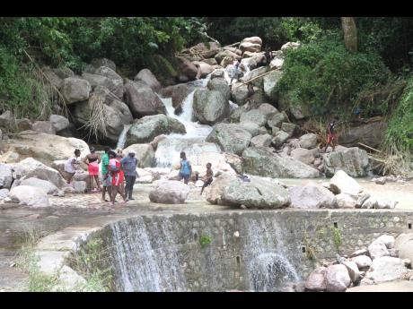 Residents at Big River gather by boulders that block the Thompson Town to Smithville main road on Saturday. The roadway became impassable because of rockslides caused by Tropical Storm Ida. 