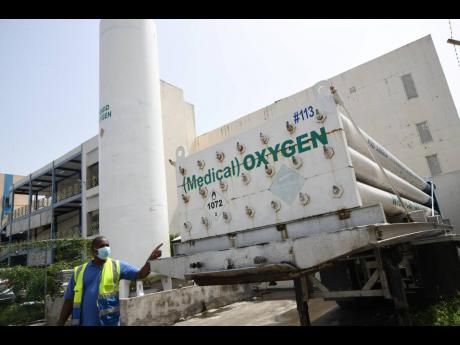 Kervin Williams, engineer of Kingston Public Hospital, shows oxygen tanks to journalists on Monday.