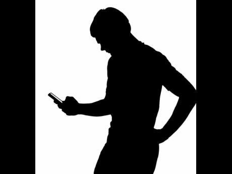 Side-profile silhouette of a teenage boy texting on smartphone. 