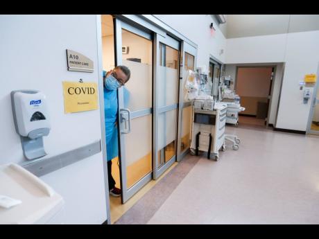 A nurse sticks her head out of a room of a COVID-19 patient in the CoxHealth Emergency Department in Springfield, Missouri. The COVID-19 pandemic has created a nurse staffing crisis that is forcing many US hospitals to pay top dollar to get the help they n