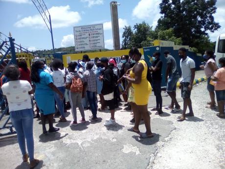 Persons swarm the entrance to Tacius Golding High School, a COVID-19 vaccination site, on Saturday.