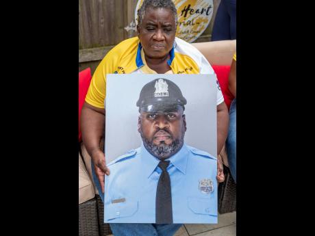 Ikelyn Tokley holds a photo of her son, Erin ‘Toke’ Tokley, a Philadelphia cop who died from COVID-19 in March at his family’s home  in Secane, Pennsylvania. He was scheduled to be vaccinated on March 11, which turned out to be the day of his funeral