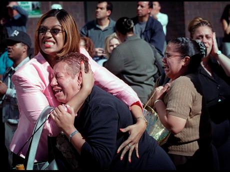 Two women hold each other as they watch the World Trade Center burn in New York Tuesday, September 11, 2001. 